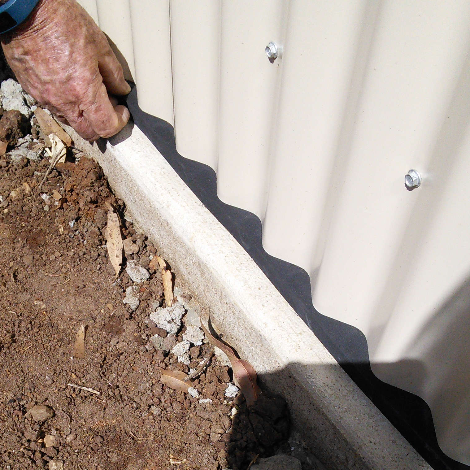 Adhesive Neoprene Foam Tape being installed to seal a garden shed floor and wall join